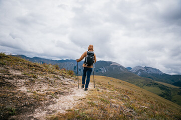 Woman backpacker hiking on high altitude mountains top
