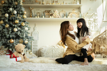 Smiling mother embracing her daughter on christmas day. Happy  girl having fun with her mother while celebration christmas festival.