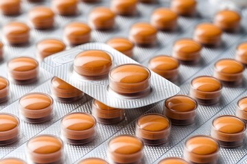 Blister pack of orange pills, focus on top transparent compartment.