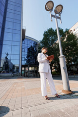 Confident Businesswoman in Stylish Striped Suit Holding Tablet in Urban Setting