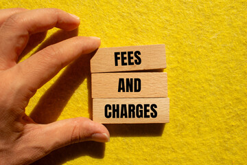 Fees and charges message written on wooden blocks with yellow background. Conceptual fees and...