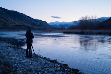 Fototapeta premium A photographer captures the serene beauty of a river flowing through a picturesque valley at twilight.