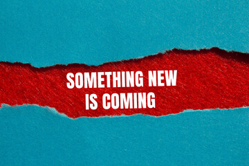 Something new is coming message written on ripped torn blue paper on red background. Conceptual...