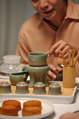 Close-up of man drinking homemade herbal tea with cakes at home