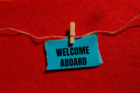 Welcome aboard message written on ripped torn blue paper piece with red background. Conceptual welcome aboard symbol. Copy space.
