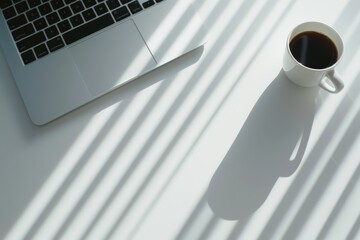 A serene workspace with a sleek laptop and a cup of coffee, bathed in gentle sunlight filtering through blinds, creating a peaceful atmosphere.