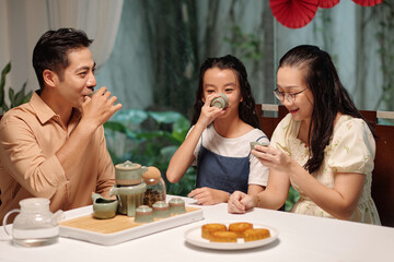 Asian family drinking green tea and eating dessert at dining room