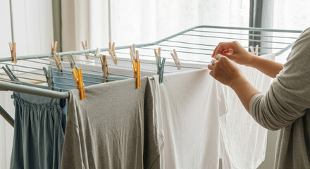 Person hanging clothes to dry indoors on drying rack