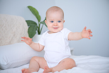 portrait of smiling healthy baby in white bodysuit sitting on bed. copy space