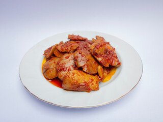 Jengkol Balado or dogfruit with red chili sauce, a spicy traditional Indonesian dish from West Sumatra, served on a white plate with a clean white background