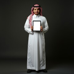 young saudi man in white thobe holding tablet isolated on dark background