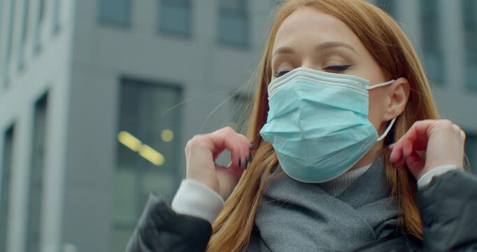 Young woman putting on medical mask for coronavirus protection outdoors. Health Protection Corona Virus Concept.