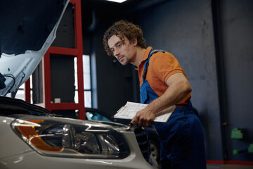 Mechanic looking under car hood checking engine operation work