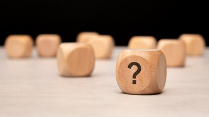 Wooden blocks featuring a prominent question mark arranged thoughtfully on a table surface