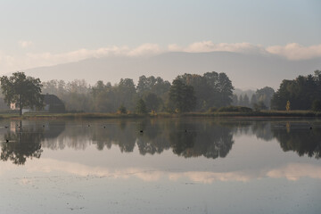 Piękny jesienny poranek nad wodą we mgle, tapeta tło. 