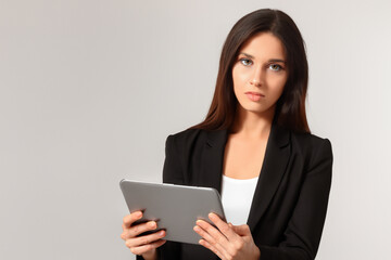 Fototapeta premium Girl in gray with tablet on the . young w female concept. girl in suit in gray with tablet on a gray . a girl in gray with a suit and a tablet on the lifestyle.