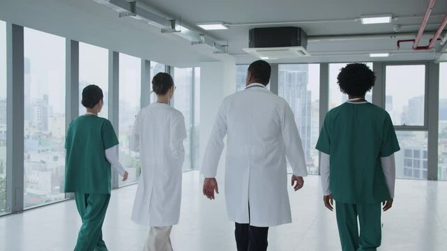 Back tracking slowmo shot of four healthcare workers in uniform going along hospital hall