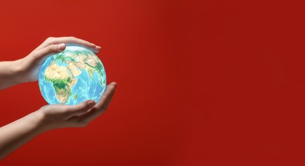 Two hands holding transparent globe against red background