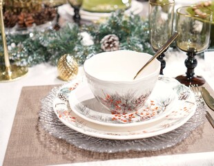 a New Year's card with a festive table setting with tea cups near the Christmas tree branches in close-up
