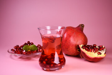 Turkish pomegranate tea in a glass glass and fresh pomegranate. Fresh mint and pomegranate seeds on the surface.