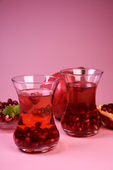 Turkish pomegranate tea in a glass glass and fresh pomegranate. Fresh mint and pomegranate seeds on the surface.