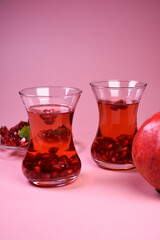 Turkish pomegranate tea in a glass glass and fresh pomegranate. Fresh mint and pomegranate seeds on the surface.
