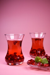 Turkish pomegranate tea in a glass glass and fresh pomegranate. Fresh mint and pomegranate seeds on the surface.