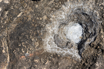 Salt deposit forming on surface of dark rock