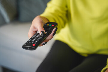 woman hand hold remote control and change television channel