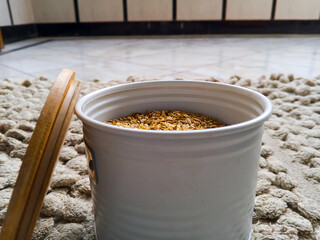 A stainless steel round container with a brown lid, filled with fennel seeds, perfect for spice storage and culinary use.