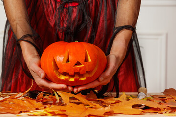 Naklejka premium Hands of woman in dress hold happy jack-o-lantern for Halloween