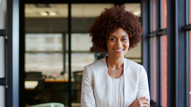Portrait Of Smiling Young Businesswoman Working In Modern Open Plan Office