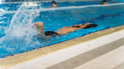 boy learning to swim in the pool with a trainer