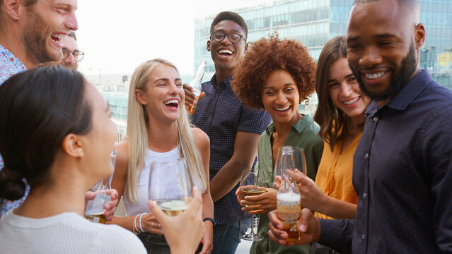 Multi-Cultural Business Team Meeting Outdoors For After Work Drinks On Office Rooftop Or Bar - Powered by Adobe