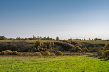 Fototapeta premium Autumn landscape with dirt road, field, far forest on hills.