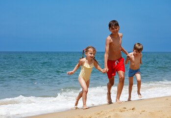Siblings, boys and girl enjoy a sunny day together at the beach
