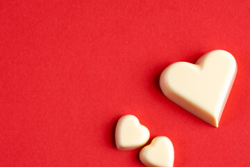 Fototapeta premium Heart in red and chocolate on a. Love holiday rtic concept. Small heart shaped chocolates on a red. A heart shaped chocolate on a white lifestyle.
