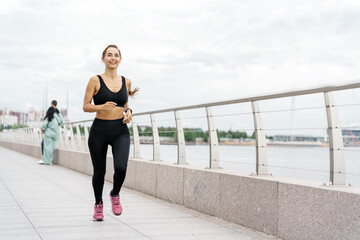 A Woman Jogs Along a Waterfront Promenade on a Cloudy Day With a Serene Atmosphere in the Background