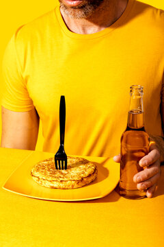 Man in yellow t-shirt enjoys food and drink in a yellow setting