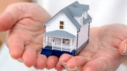 model of a house in a woman's hands