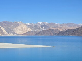 Serene Mountain Lake: A panoramic view of a tranquil lake nestled in the Himalayas, showcasing a breathtaking vista of majestic mountains and a pristine shoreline.