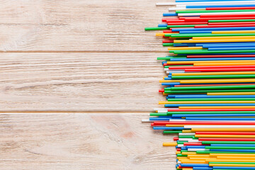 Fototapeta premium Heap of colorful plastic drinking straws on Colored background, flat lay. Copy Space for text