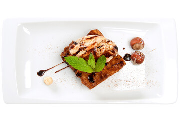Overhead shot of sweet crispbread dessert with caramel, vanilla ice cream scoop and almond garnish on white plate on wooden background