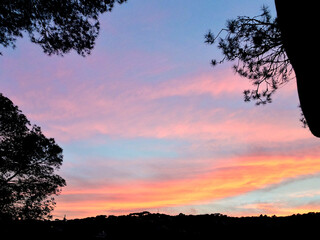 Group of scattered clouds in gradients from yellow to blue with mountainous outline in the image frame