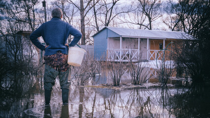 a man looks at a flooded house after a flood