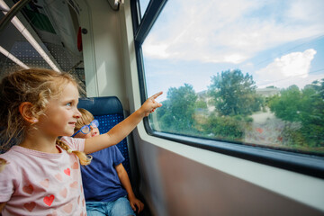 Excited girl enjoys a train journey, pointing out the window