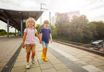 Obraz premium Little travelers walking at the train station, holding hands