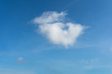 Fluffy white clouds drift across a clear blue sky, painting a beautiful summer landscape