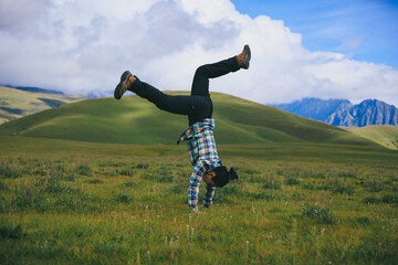 Woman hiker doing a handstand on high altitude mountain top grassland