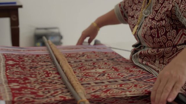 A woman weaving pua kumbu traditional cloth patterns at home